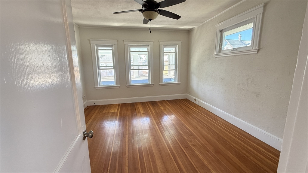 12 Eliot Street, Unit 12 Medford, MA 02155 - Photo 8 of 11 an empty room with wooden floor chandelier fan and windows