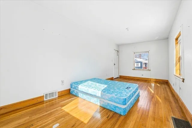 a bedroom with a bed and a wooden floor