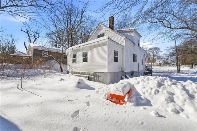 a view of a white house with a yard covered in snow