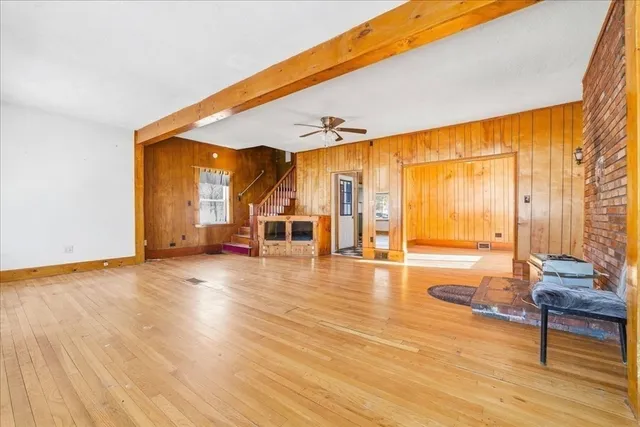 a view of an empty room with wooden floor and a large window