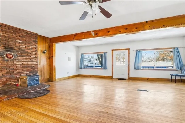 a view of an empty room with window and wooden floor