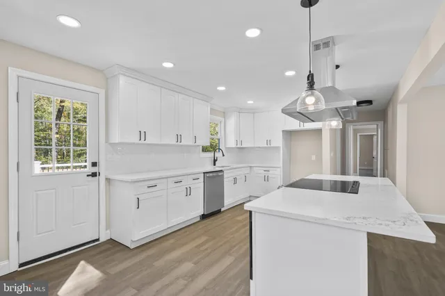 a kitchen that has a lot of white cabinets and wooden floor