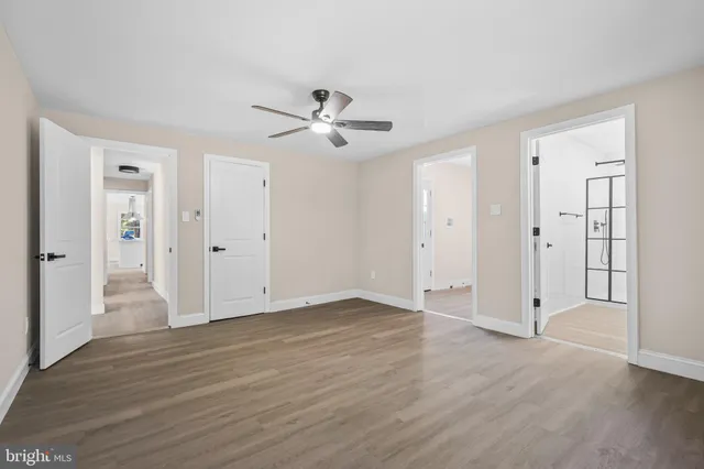 a view of empty room with wooden floor and ceiling fan