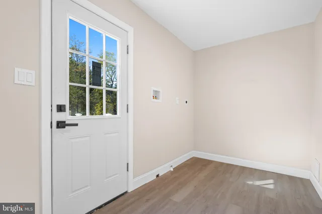 a view of an empty room with wooden floor and windows
