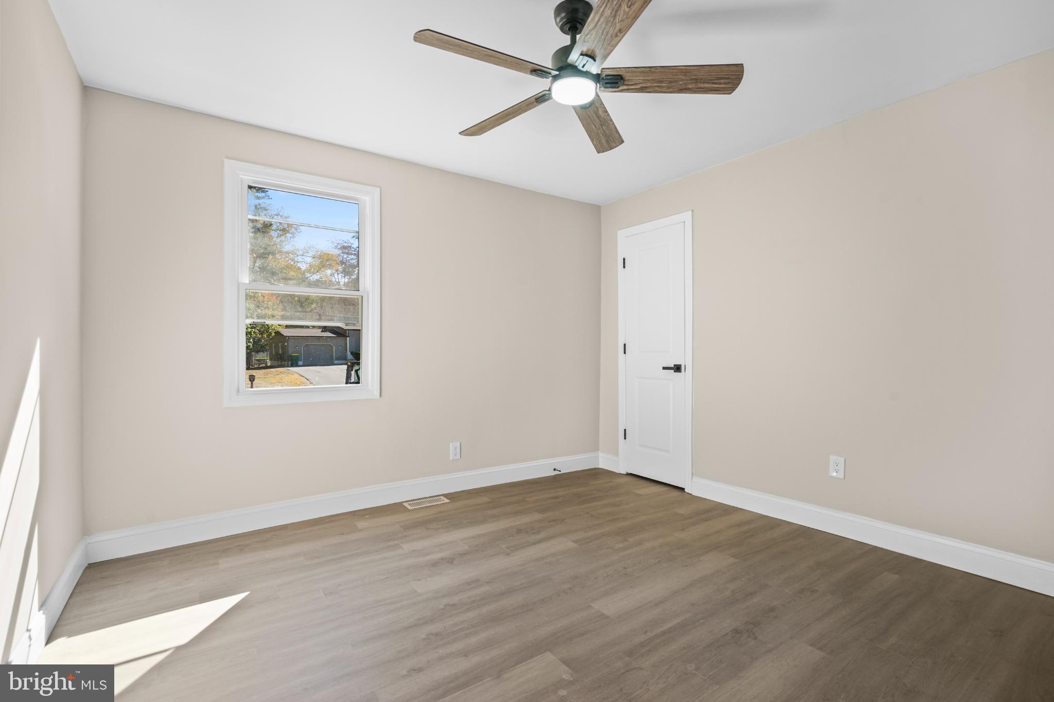393 East Millstream Road Cream Ridge, NJ 08514 - Photo 21 of 29 an empty room with wooden floor ceiling fan and windows