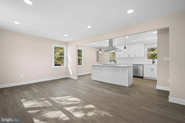 a large white kitchen with a sink a window and stainless steel appliances