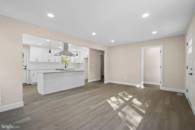 a large white kitchen with kitchen island a sink wooden floor and stainless steel appliances