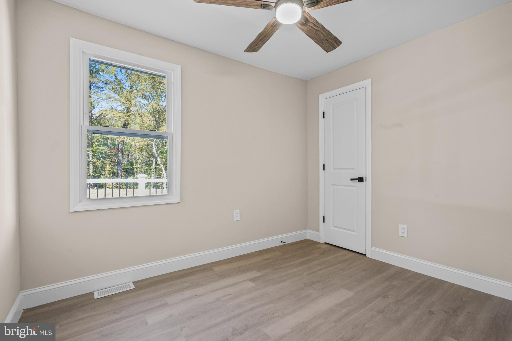 393 East Millstream Road Cream Ridge, NJ 08514 - Photo 7 of 29 an empty room with wooden floor chandelier fan and windows