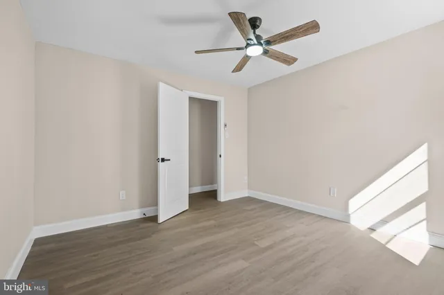 an empty room with wooden floor ceiling fan and window