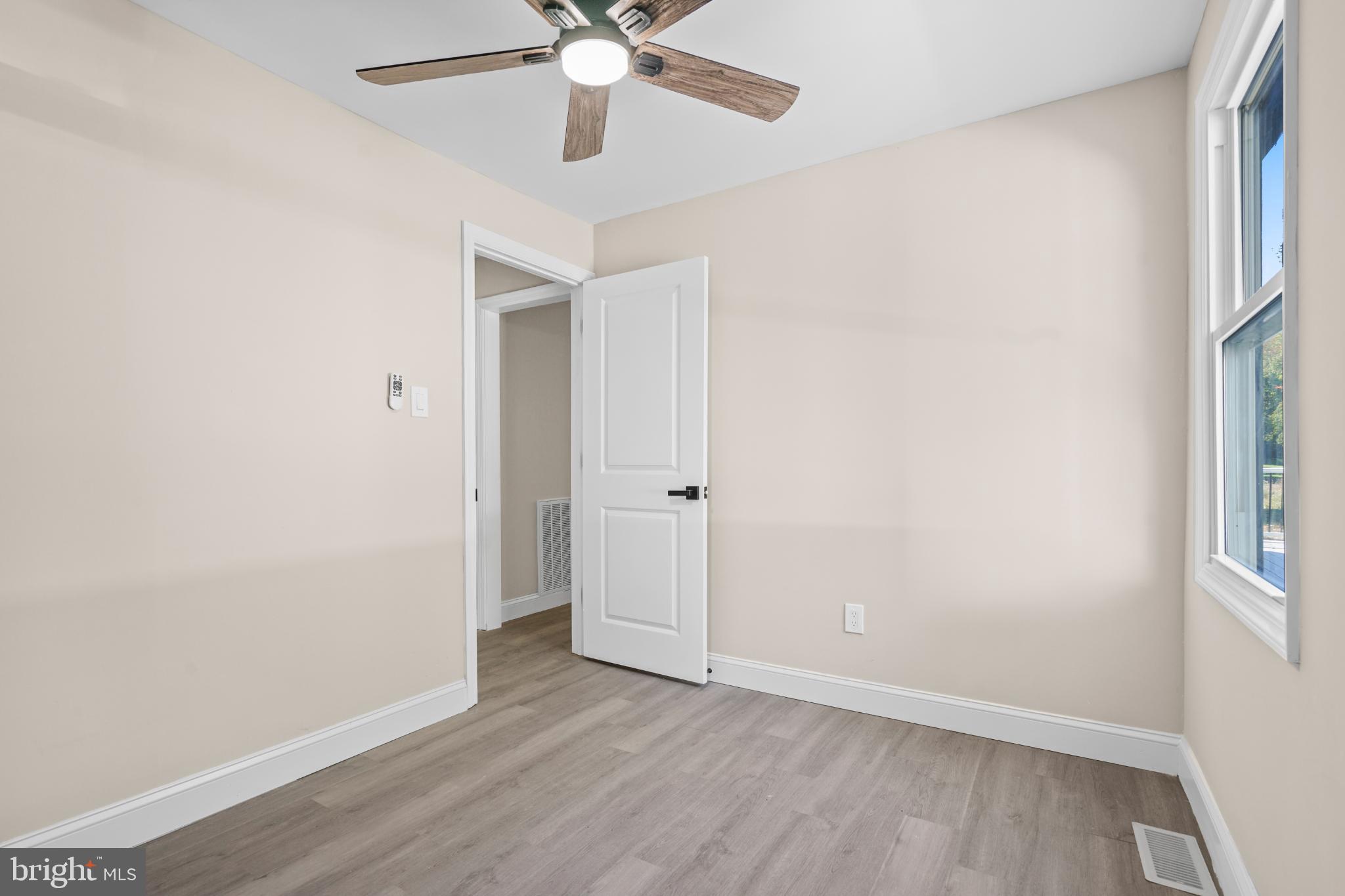 393 East Millstream Road Cream Ridge, NJ 08514 - Photo 9 of 29 an empty room with wooden floor chandelier fan and windows