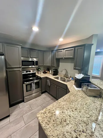 a kitchen with stainless steel appliances granite countertop a refrigerator sink and stove