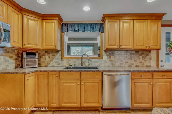 a kitchen with granite countertop wooden cabinets a sink and dishwasher