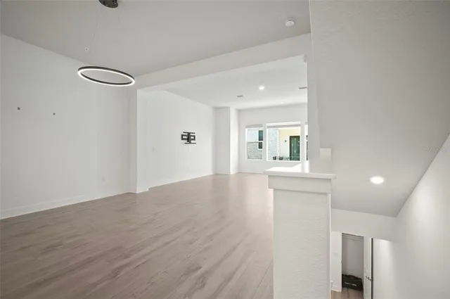 a view of a hallway with wooden floor staircase and a kitchen