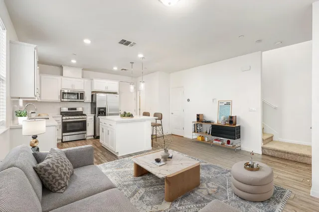 a living room with furniture a table and kitchen view