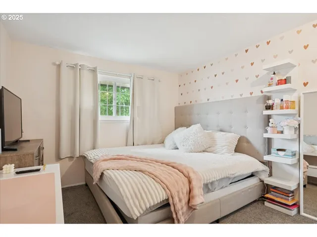 a bedroom with a bed and a flat tv screen on the dresser