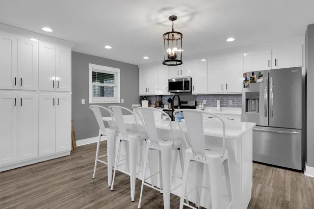 a kitchen with stainless steel appliances kitchen island refrigerator stove dining table and chairs