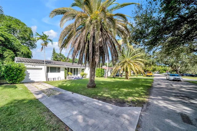 front view of house with a yard and palm trees