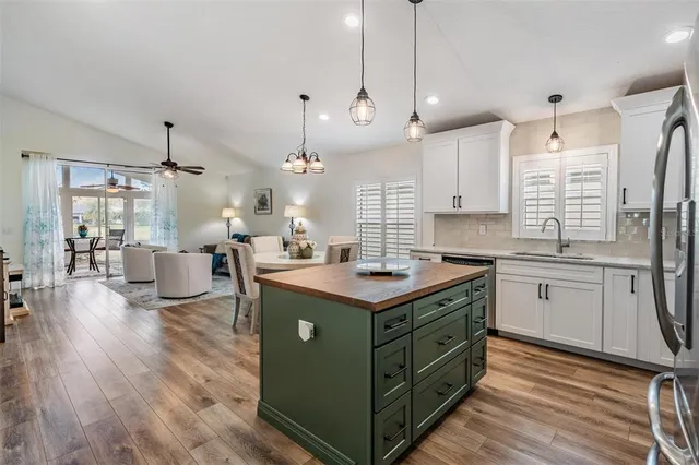 a living room with couches and kitchen view with wooden floor