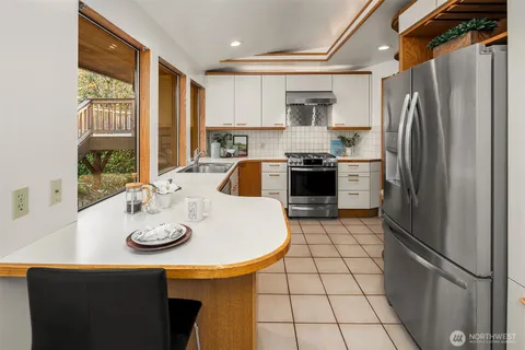 a kitchen with stainless steel appliances a refrigerator a stove a sink and a dining table with wooden floor