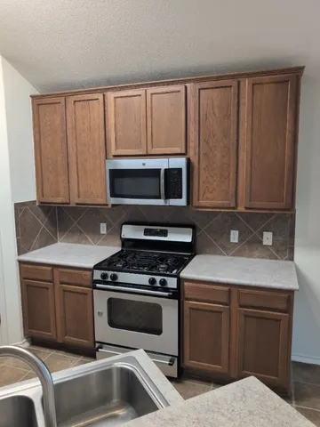 a kitchen with stainless steel appliances granite countertop a stove microwave and sink