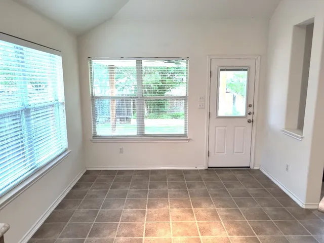 an empty room with chandelier fan and windows