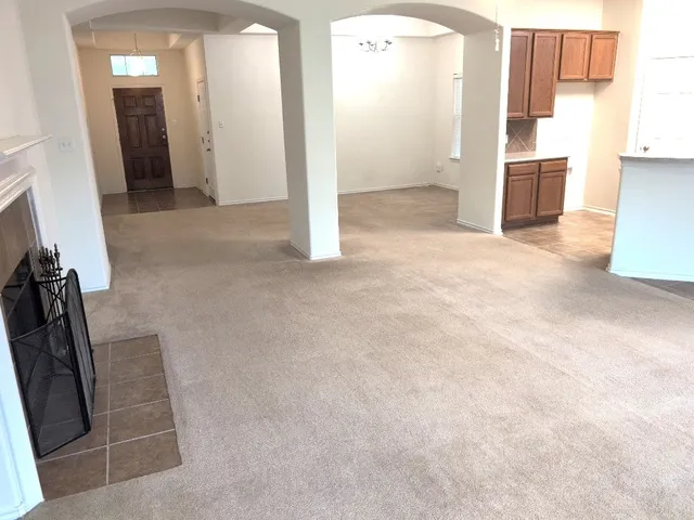 a view of a refrigerator in kitchen and an empty room
