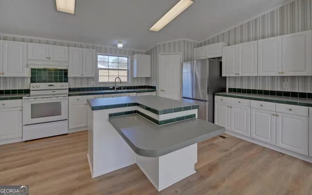 a kitchen with stainless steel appliances granite countertop a stove top oven a sink and white cabinets