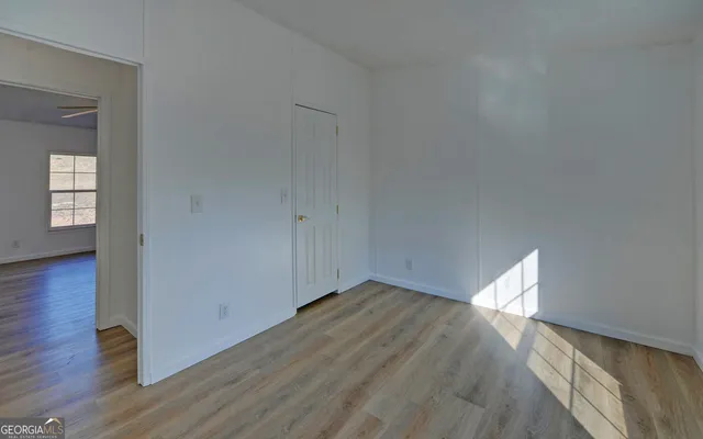 a view of empty room with wooden floor and fan