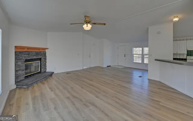 a view of empty room with kitchen and fireplace