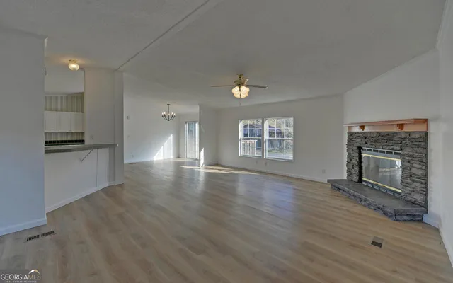 an empty room with wooden floor fireplace and windows