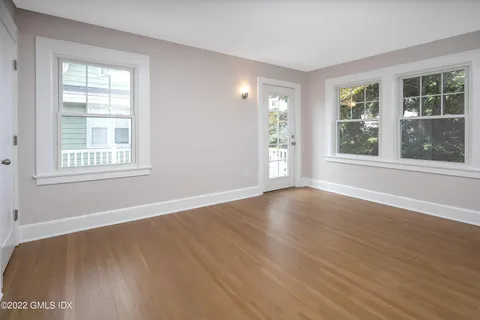 a view of an empty room with wooden floor and windows