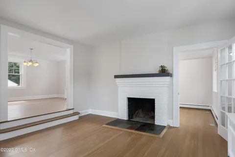 a view of an empty room with wooden floor and a fireplace
