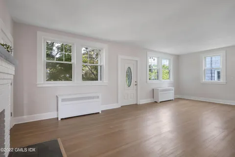 a view of an empty room with a window and wooden floor
