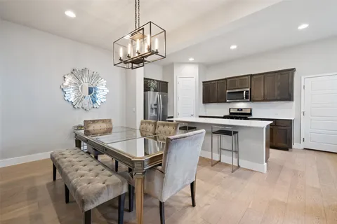 a kitchen with stainless steel appliances kitchen island granite countertop a sink dishwasher a stove a refrigerator a microwave oven with a dining table and chairs