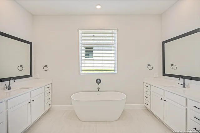 a spacious bathroom with double vanity sink a mirror and a bathtub