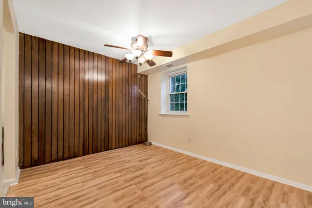 an empty room with wooden floor chandelier fan and windows