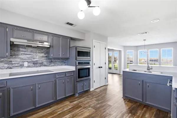 a kitchen with stainless steel appliances granite countertop a sink cabinets and wooden floor