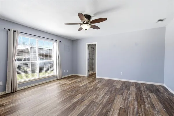 a view of empty room with wooden floor and fan