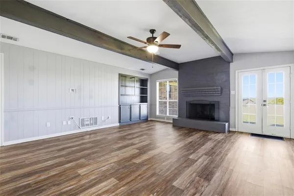 a view of empty room with wooden floor and fireplace