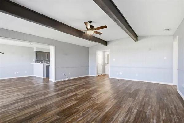 a view of an empty room with wooden floor and a ceiling fan