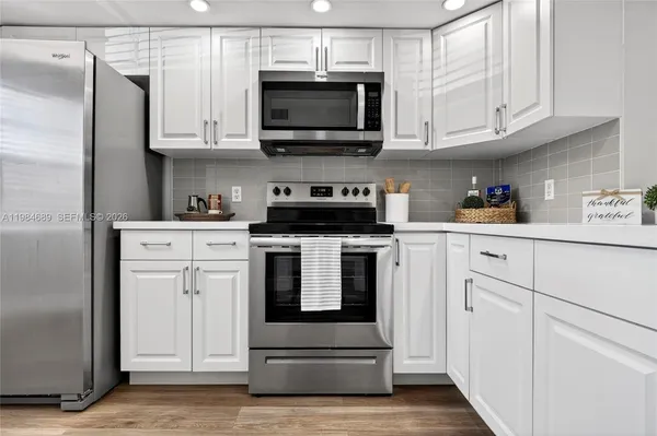 a kitchen with white cabinets and stainless steel appliances