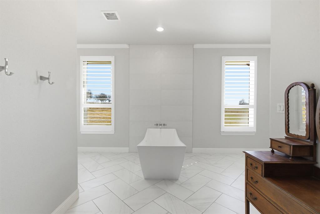4600 Old Brock Road Weatherford, TX 76087 - Photo 23 of 37 Freestanding soaking tub with a tiled surround, framed by two windows with plantation shutters