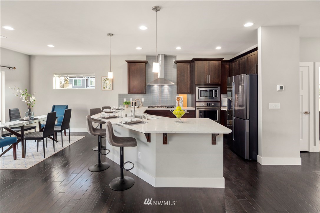 7 176th Place Southeast Bothell, WA 98012 - Photo 14 of 40 a kitchen with stainless steel appliances kitchen island granite countertop a refrigerator a stove a sink a dining table and chairs with wooden floor