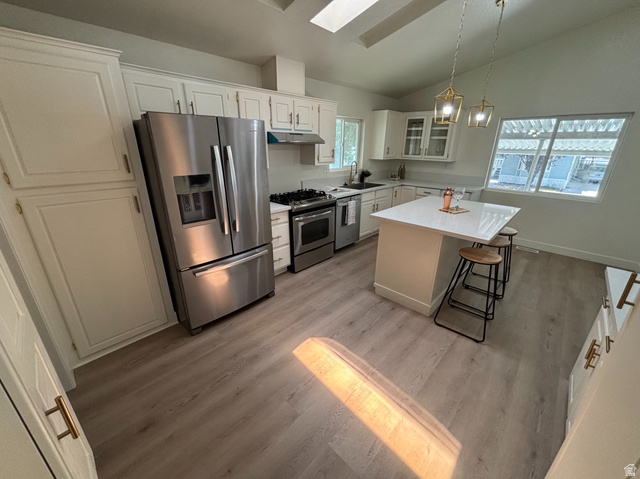11313 South 265 East Sandy, UT 84070 - Photo 4 of 21 Kitchen featuring white cabinetry, stainless steel appliances, a center island with a white countertop, and wood-finish flooring