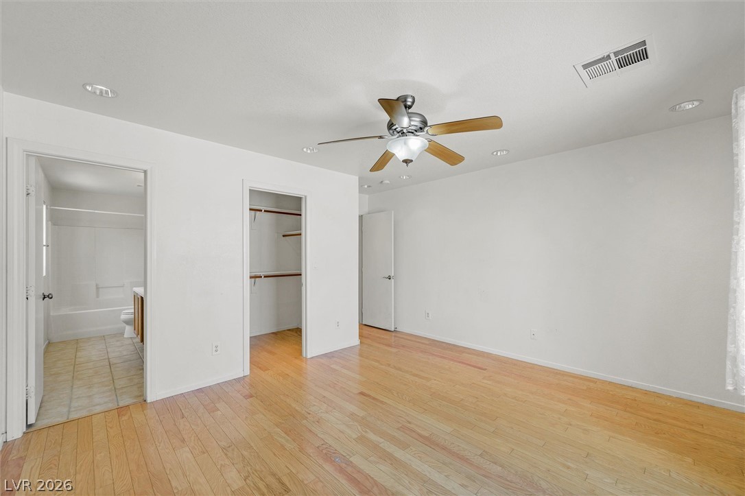 6762 Arapaho Ranch Las Vegas, NV 89148 - Photo 4 of 27 Hardwood flooring extends through this well-lit room, featuring a practical ceiling fan and an adjacent bathroom.
