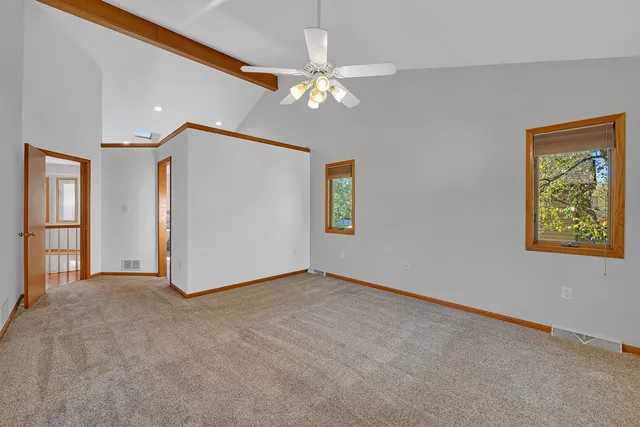 a view of an empty room with window and chandelier fan