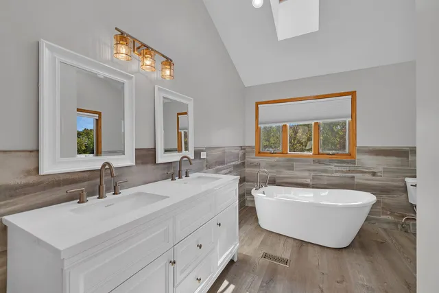 a bathroom with a double vanity sink mirror and bathtub