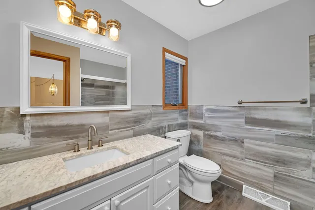 a bathroom with a granite countertop toilet sink and mirror