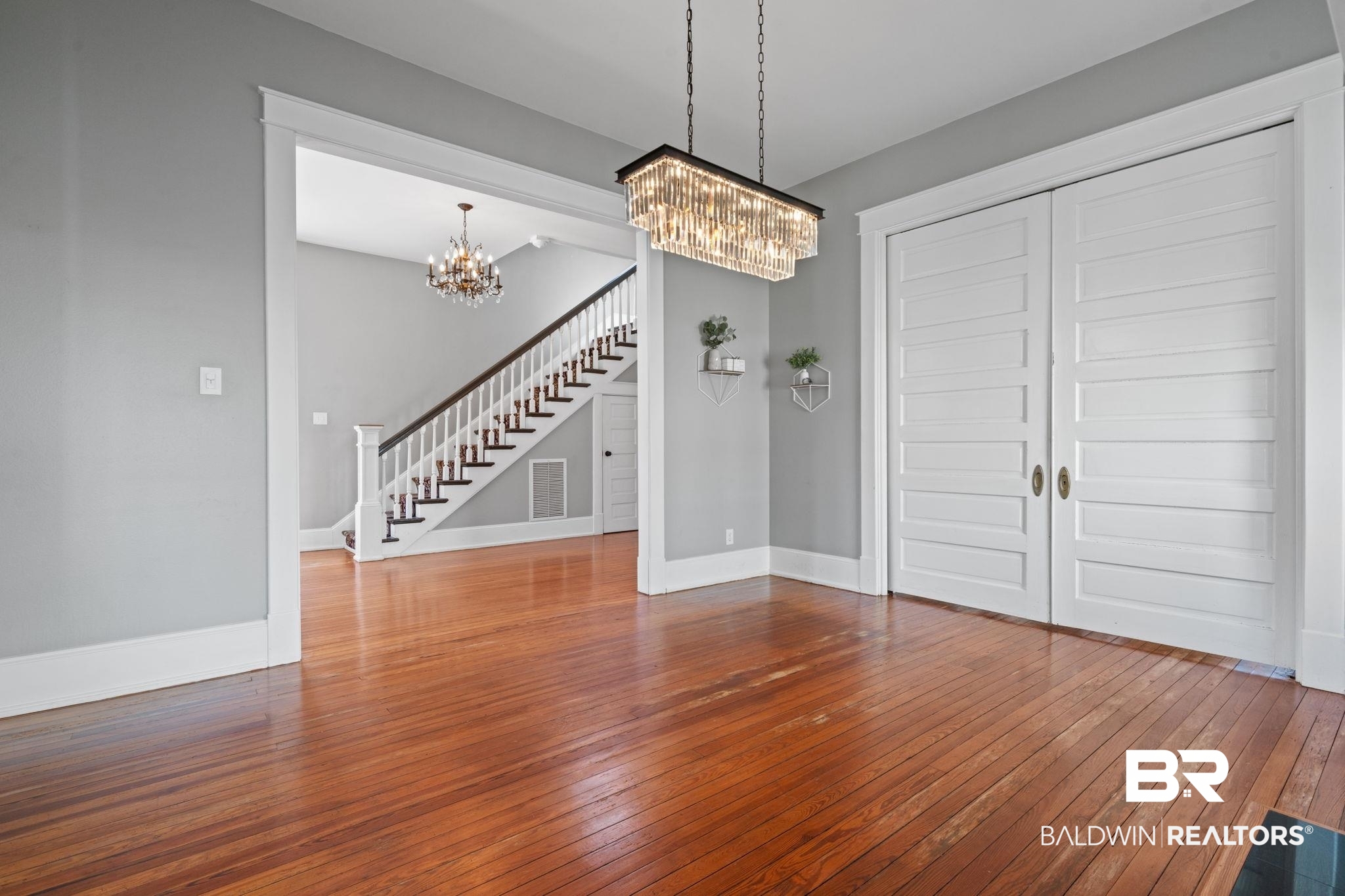 10 South Monterey Street Mobile, AL 36604 - Photo 10 of 45 Unfurnished living room with wood-type flooring, stairway, and a chandelier
