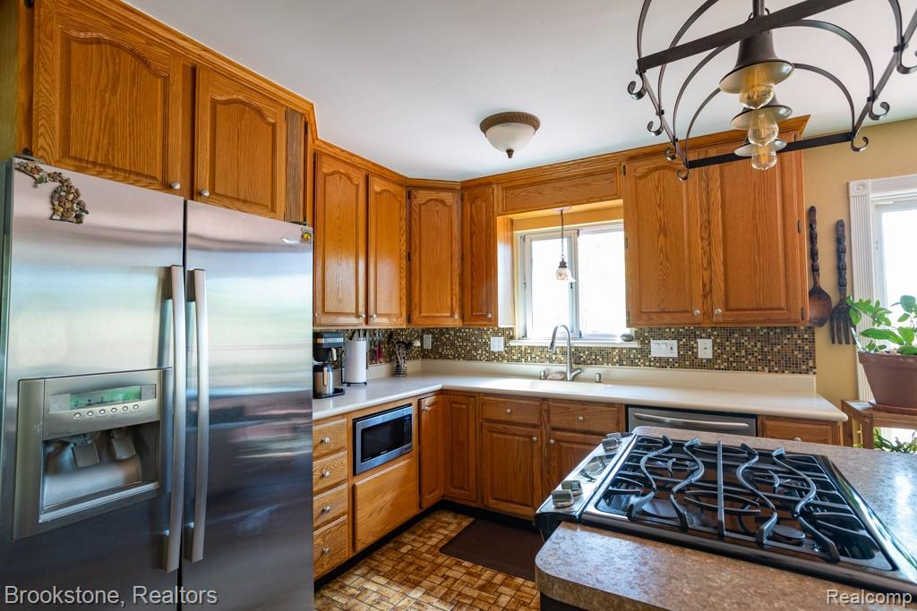 30100 Armada Ridge Road Richmond, MI 48062 - Photo 8 of 29 Kitchen featuring wood cabinetry, stainless steel appliances, mosaic tile backsplash, a built-in gas cooktop, and a double basin sink beneath a window